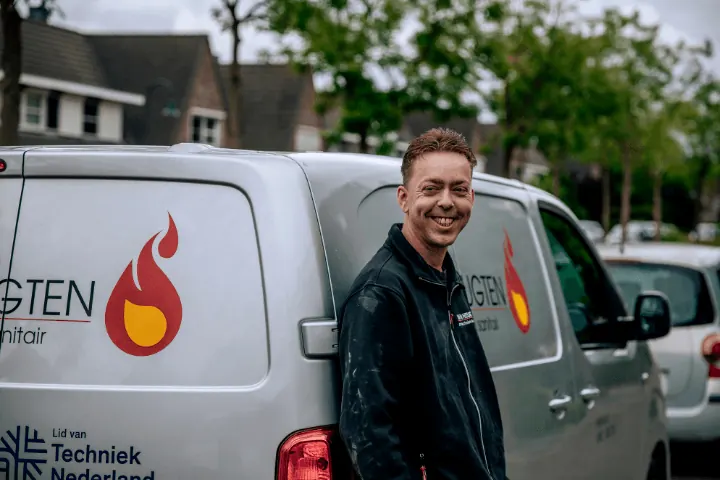 Lachende vakman van Van Heugten voor de bedrijfsbus met het vlamlogo